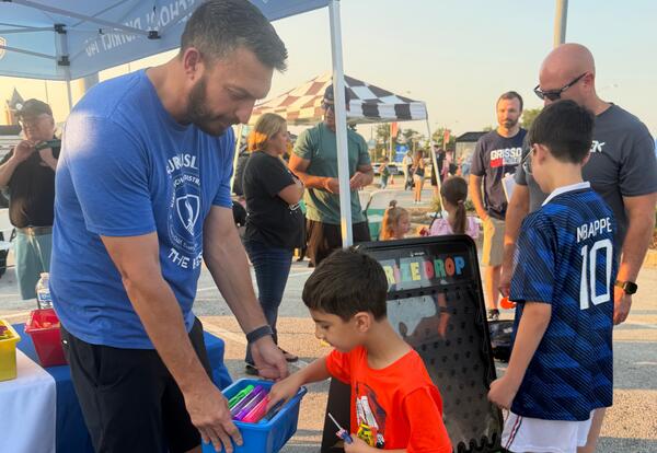 Student picking out prize in bucket held by principal at National Night Out