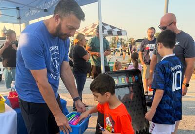 Student picking out prize in bucket held by principal at National Night Out