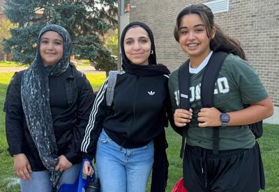 Three students smile outside on the first day of school