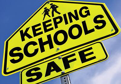 Yellow sign with Keeping School Safe written on it with blue sky in background