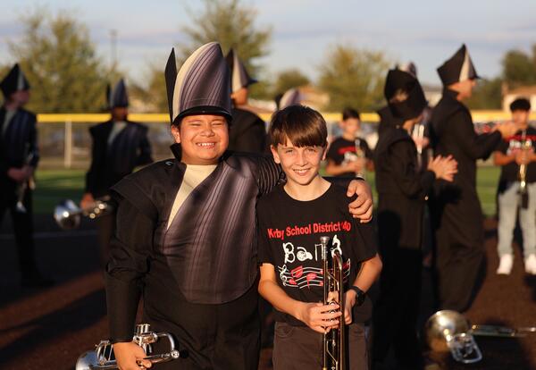 High school and KSD 140 band students pose on football field holding their instruments