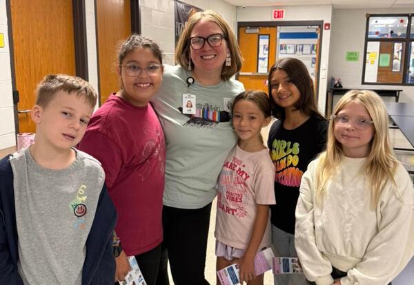 Librarian poses with 5 elementary students