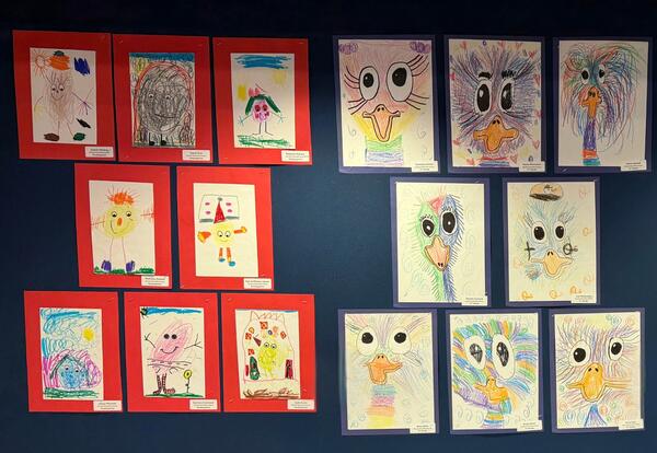 A wall display featuring students' artwork, including birds and figures
