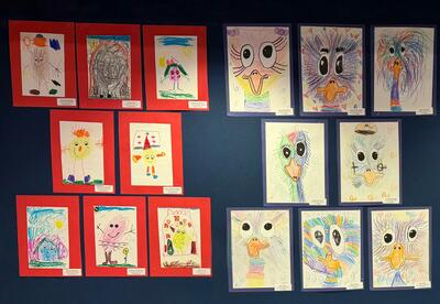 A wall display featuring students' artwork, including birds and figures