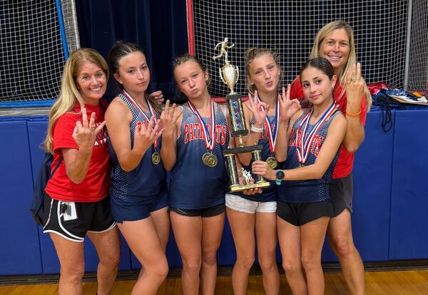 Cross country athletes pose with coaches with medals and trophy after winning third conference championship