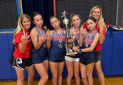 Cross country athletes pose with coaches with medals and trophy after winning third conference championship