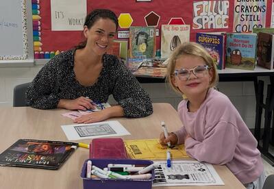 Student and parent sitting at table in classroom working on a project during Family Reading Night