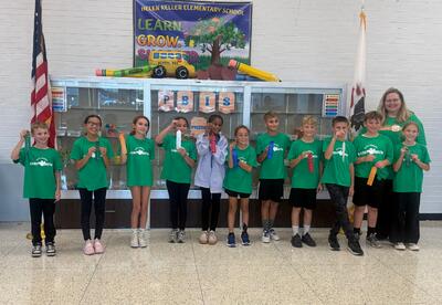 Students pose proudly with teacher and ribbons won for annual ghost buster race