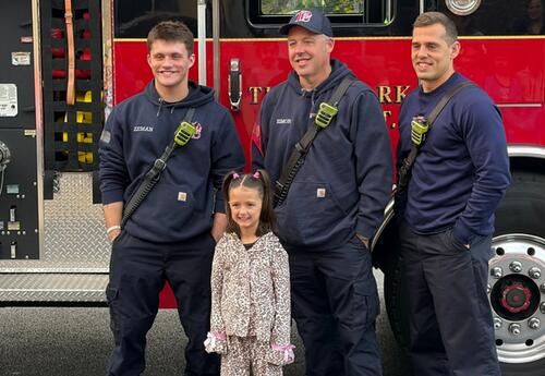Fire prevention poster winner poses with fire fighters in front of fire truck outside of  school after getting a ride to school