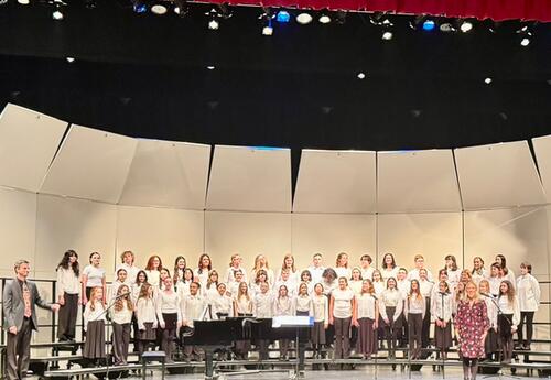 D140 middle school choruses standing on stage with chorus directors during fall concert at Andrew high school