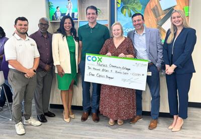Representatives from Cox Communications and Nunez Community College pose with an oversized donation check.