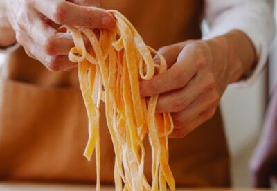 A closeup of someone making fettuccine noodles by hand.