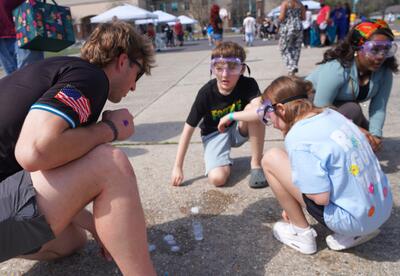 A Nunez baseball player assists children with an experiment during the Bayou Blast Off event.