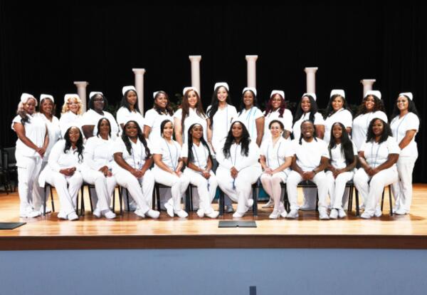 Nunez's Spring 2026 Practical Nursing Graduates pose for a photo on stage in the Nunez Auditorium