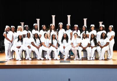 Nunez's Spring 2026 Practical Nursing Graduates pose for a photo on stage in the Nunez Auditorium