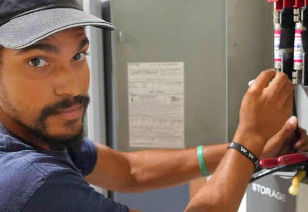 An electrician works in a fuse box in the Nunez Aerospace building.