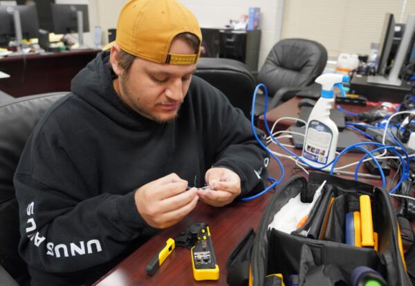 An IT technician works on a piece of wiring.