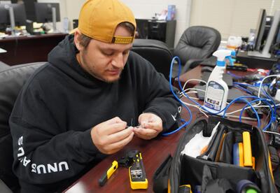 An IT technician works on a piece of wiring.
