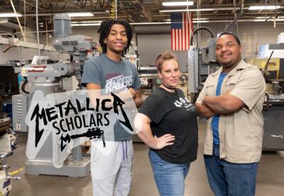 three students standing in machine lab posing advertising Metallica Scholars initiative