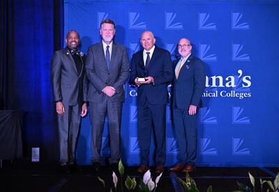 four men standing on stage accepting award