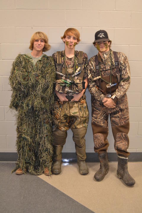 Three students in grass and regular camouflage