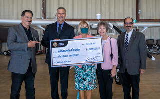 Superintendent and HCSD School Board members holding large check