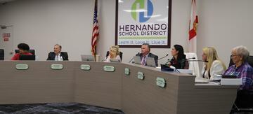 Santiago Pinkney sitting with the school board at the Dais