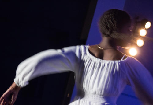 Picture of an ASH student dancing on stage in atmospheric lighting.