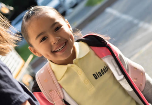 Smiling girl getting welcomed into school