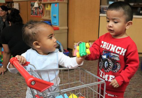 A toddler and baby share a toy during Arbor Hill Elementary School's twice-monthly playgroup.