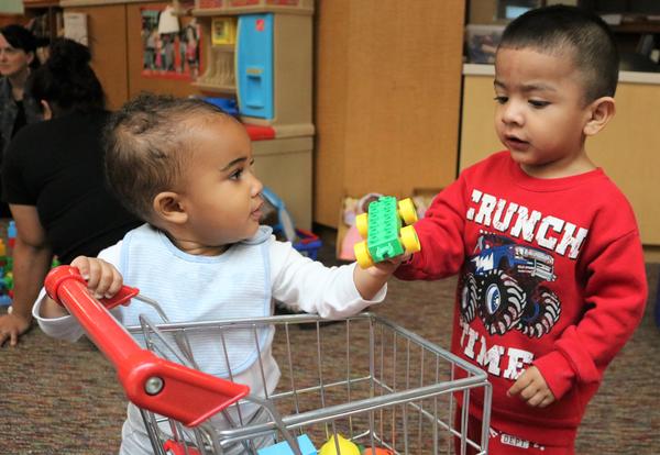 A toddler and baby share a toy during Arbor Hill Elementary School's twice-monthly playgroup.