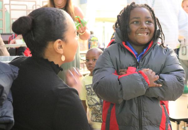 A volunteer assists a student as he tries on a new winter coat to make sure it fits.