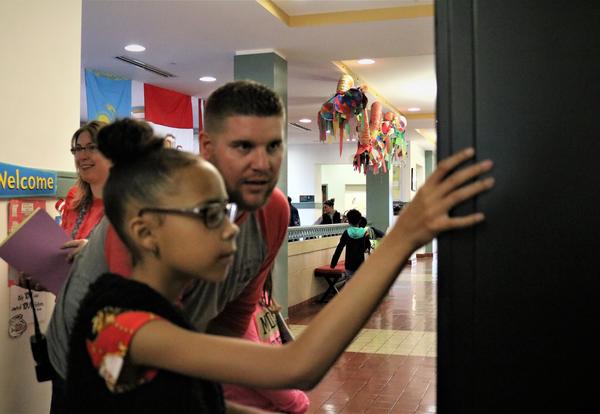 Assistant Principal Glenn Westfall helps a student choose a book from the ASH book vending machine.