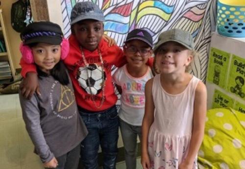 Four Albany School of Humanities students pose wearing hats.