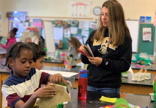 Two students create plastic bottle and tissue paper lanterns in art class.