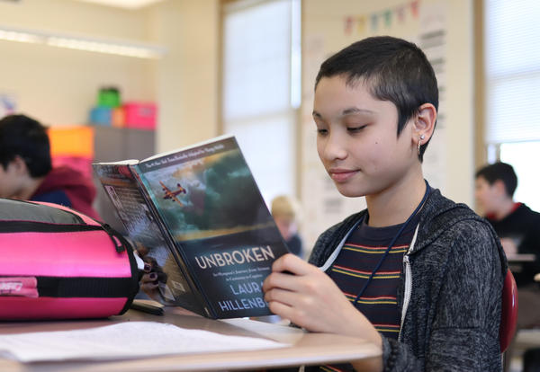 Student reading a book at their desk.