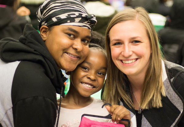 Mother, daughter and teacher smile at community dinner