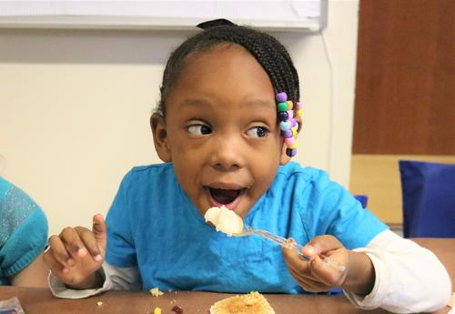 A kindergarten student enjoys a plate full of Thanksgiving food.