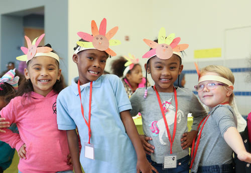 Group of  four students posing for a picture wearing turkey headbands made from construction paper.