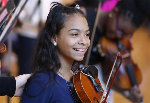 Student smiling with their violin during the winter concert performance.