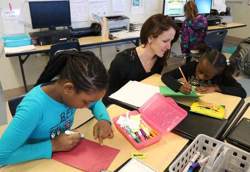 A teacher and two students create Christmas cards.