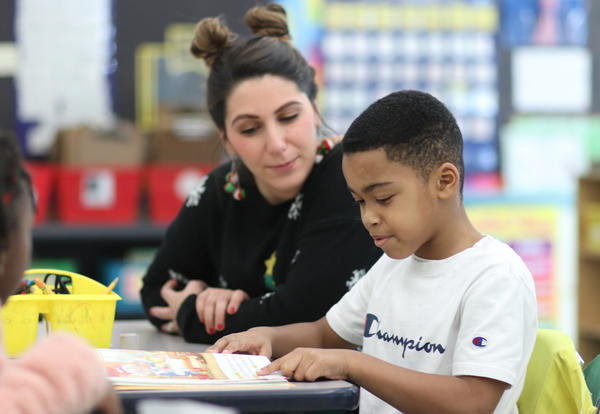 Student reading a book with Ms. Crisorio.