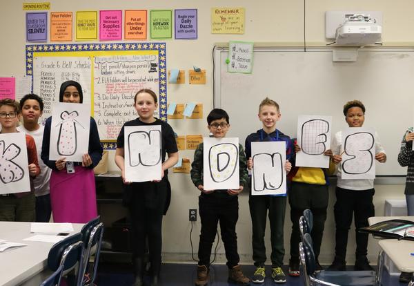 Sixth-graders hold up letters spelling out the word kindness.