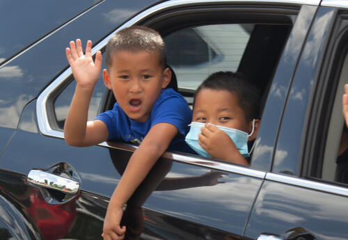 Two boys wave from a car window