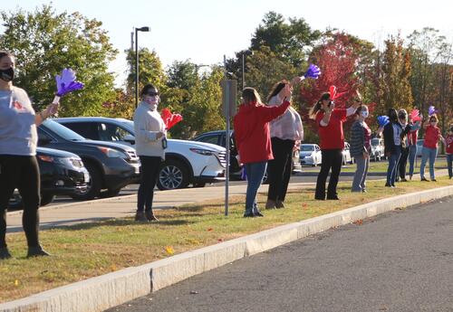 Teachers wave to students in a drive by parade.