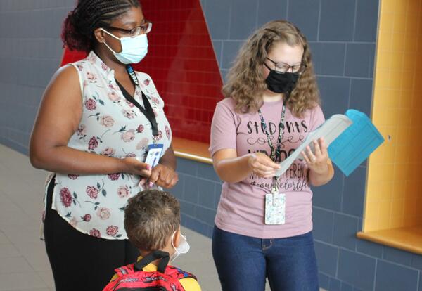 Staff help a student find their classroom on the first day of school.