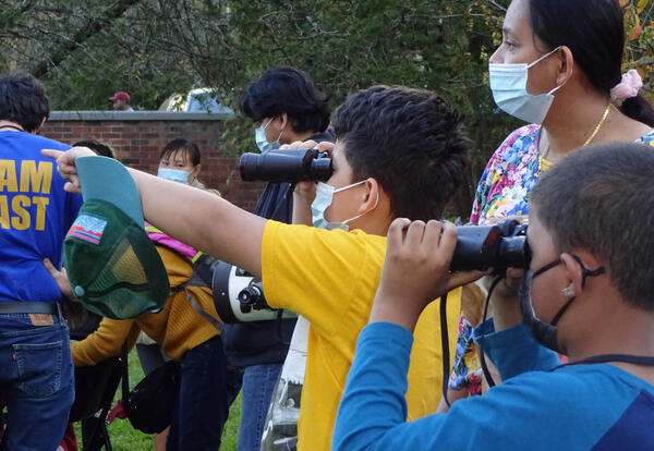 A boy, a girl and a woman look through binoculars