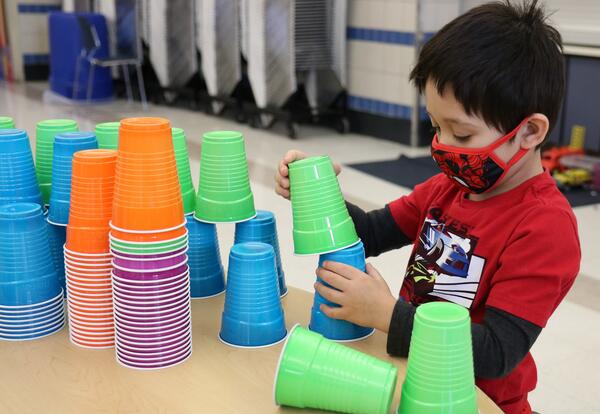 A student builds with plastic cups on the 100th Day of School.