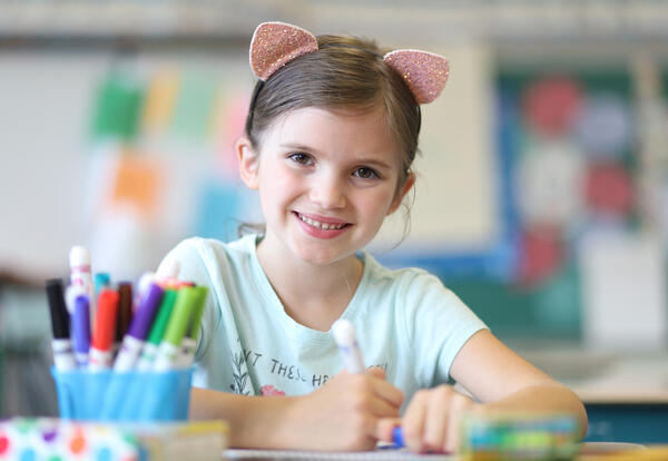 Smiling girl draws on paper