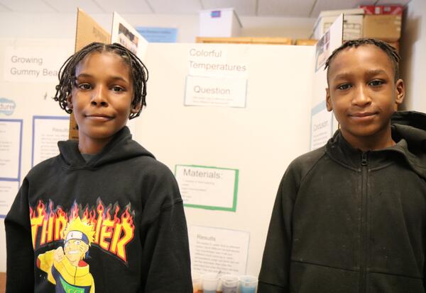 Two students pose in front of their science fair posterboard